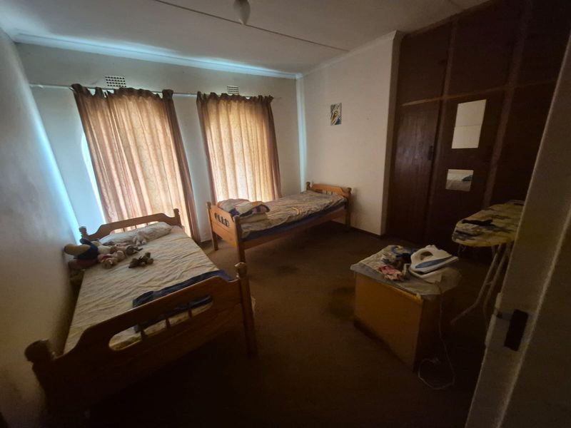 A bedroom featuring built-in wooden cupboards and carpeted flooring, offering a functional space with potential for modernization.