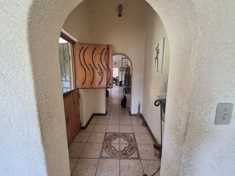 Entrance hall featuring a distinctive arched doorway, textured walls, and tiled flooring with a decorative central inlay.
