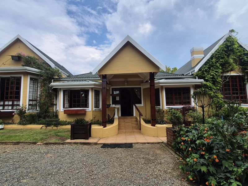 A charming single-story house featuring a covered entrance porch, timber-framed windows, and a well-maintained brick facade with established climbing greenery.