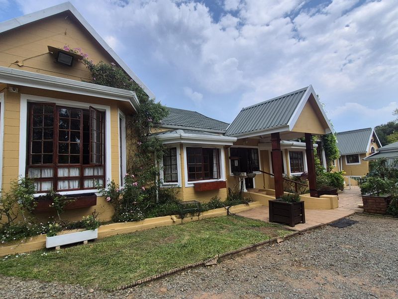 Front elevation of a charming house featuring a metal roof, timber-framed windows, and a covered entrance porch with timber columns.