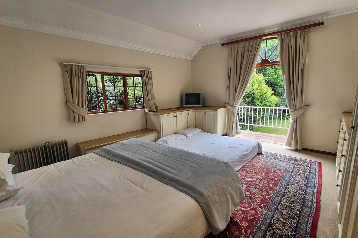 Spacious bedroom featuring vaulted ceilings, built-in cabinetry, and direct access to a private balcony overlooking the garden.