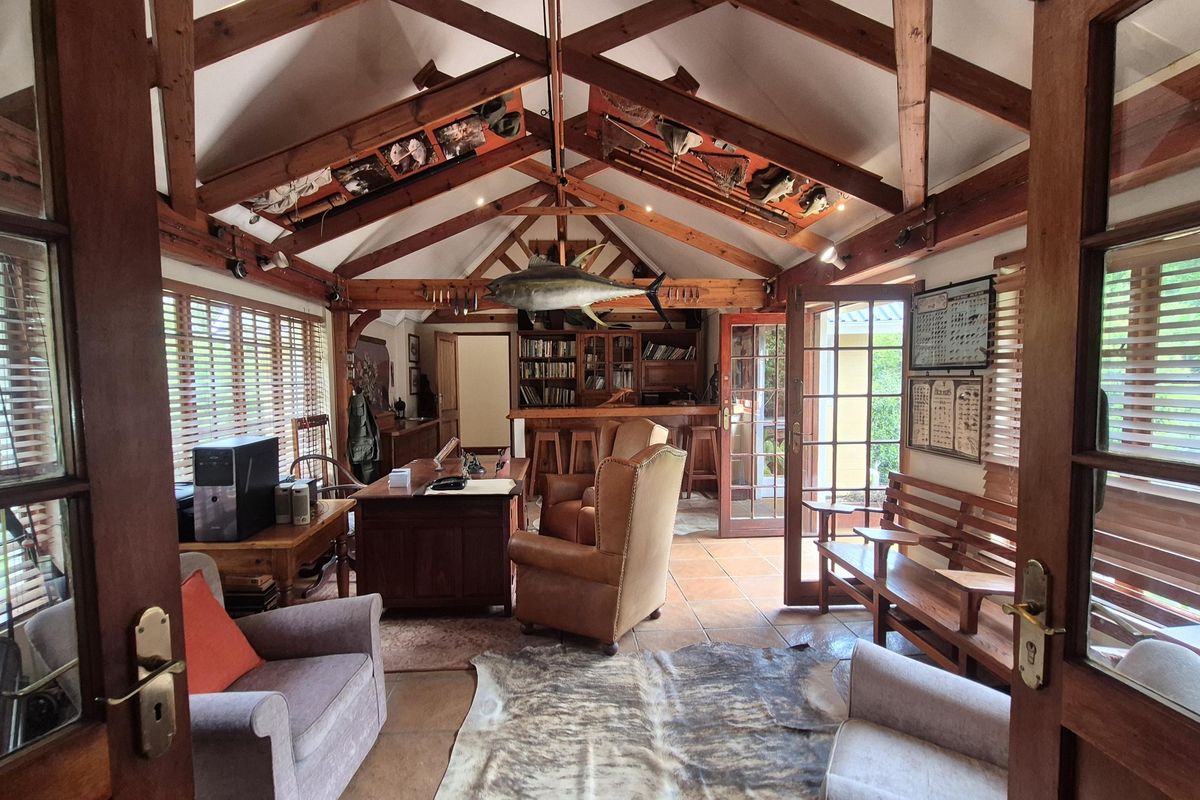 Spacious living area featuring vaulted ceilings with exposed timber trusses, tiled flooring, and a built-in wooden bar, offering a warm and rustic atmosphere.
