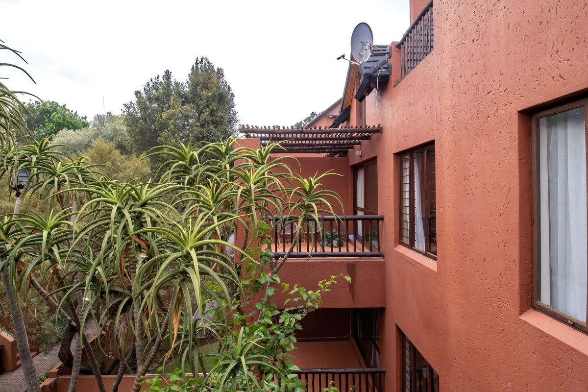 Rear elevation of the apartment building featuring stacked balconies with timber pergolas, railings, and views of the surrounding garden area.