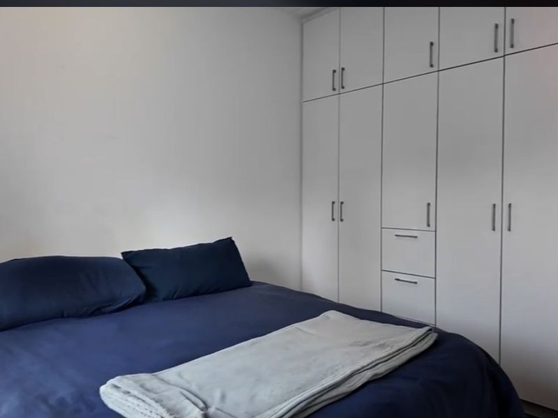 A bedroom featuring white built-in cupboards providing ample storage space.