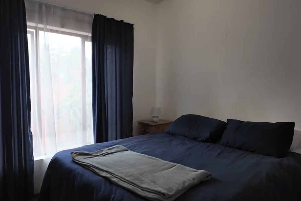 A simple bedroom featuring a large window with curtain tracks, providing natural light and a neutral backdrop for personalization.