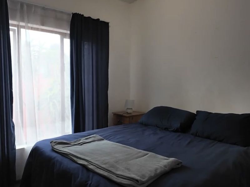 A simple bedroom featuring a large window with curtain tracks, providing natural light and a neutral backdrop for personalization.
