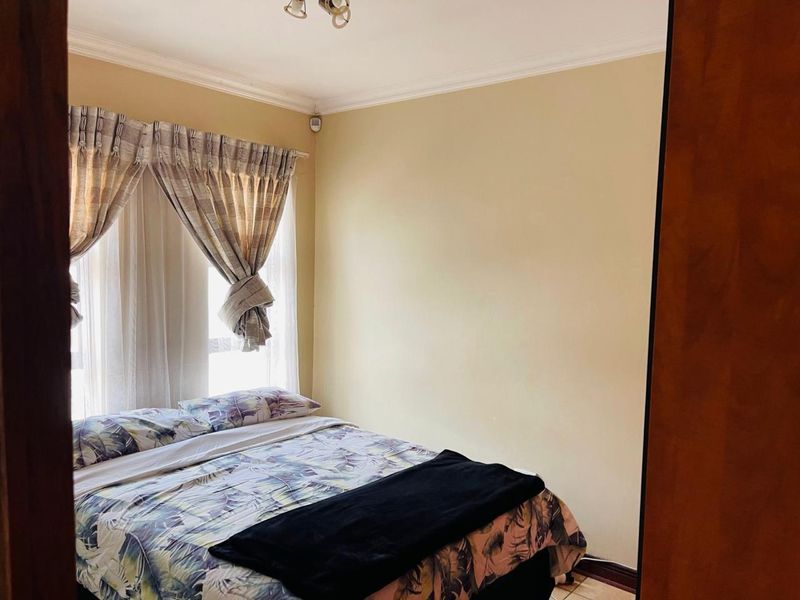 A standard bedroom featuring tiled flooring, ceiling cornice detailing, and a wall-mounted security camera.