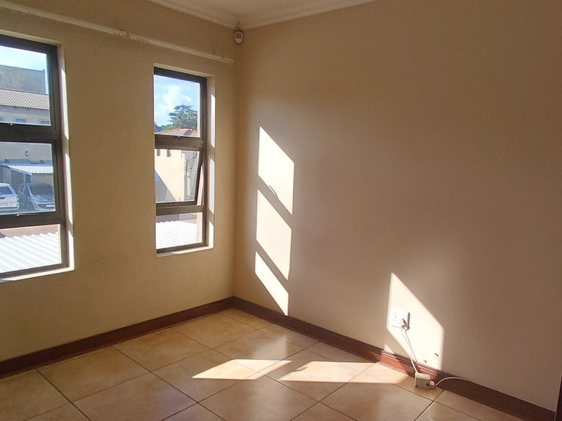 A bright, empty bedroom featuring tiled flooring and aluminium-framed windows, offering a clean and neutral space ready for personalization.