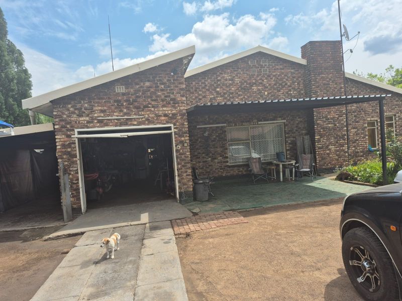 Front view of a brick house featuring a garage, a covered patio area, and a concrete driveway.