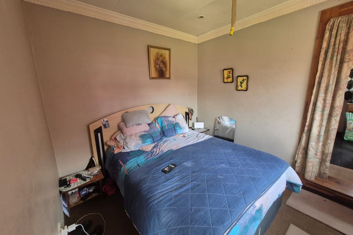 A bedroom featuring crown molding and a wooden door frame, currently showing signs of wear including damaged ceiling and exposed wiring.