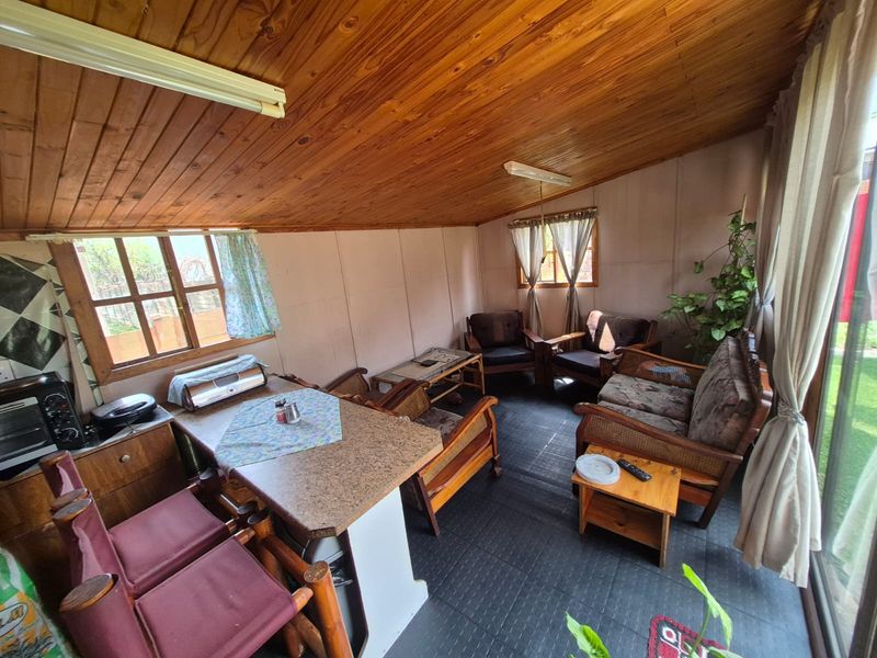 Open-plan living area featuring a timber-clad ceiling, laminate flooring, and a built-in breakfast bar with direct access to the outdoor space.
