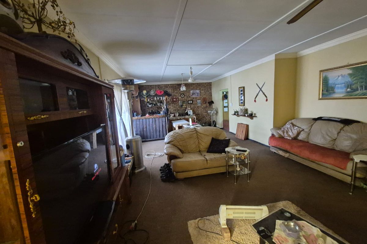 Spacious living area featuring an exposed brick accent wall, coved ceilings, and a ceiling fan, offering potential for modernization.