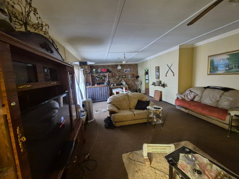 Spacious living area featuring an exposed brick accent wall, coved ceilings, and a ceiling fan, offering potential for modernization.