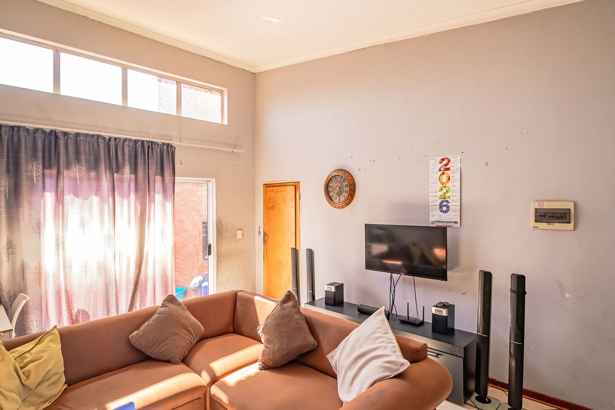 A living room featuring high ceilings with clerestory windows, providing natural light and access to an outdoor area through a sliding glass door.