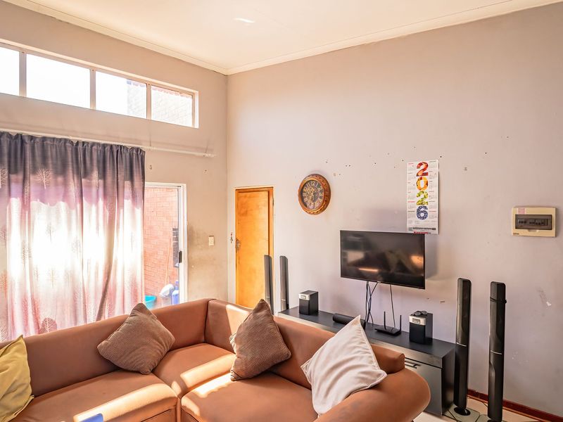 A living room featuring high ceilings with clerestory windows, providing natural light and access to an outdoor area through a sliding glass door.