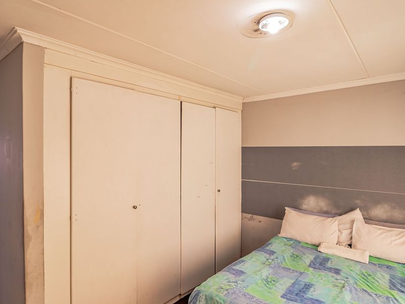 A bedroom featuring built-in cupboards and a ceiling light fixture, requiring cosmetic updates to the wall finishes and cabinetry.