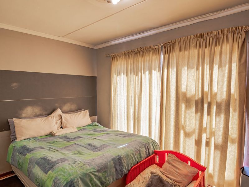 A bedroom featuring a sliding door with curtains and painted wall accents, showing signs of wear and surface damage requiring maintenance.