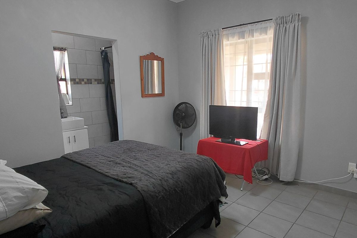 A functional bedroom featuring tiled flooring, a built-in wardrobe, and direct access to an en-suite bathroom.
