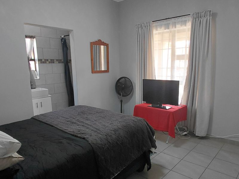 A functional bedroom featuring tiled flooring, a built-in wardrobe, and direct access to an en-suite bathroom.
