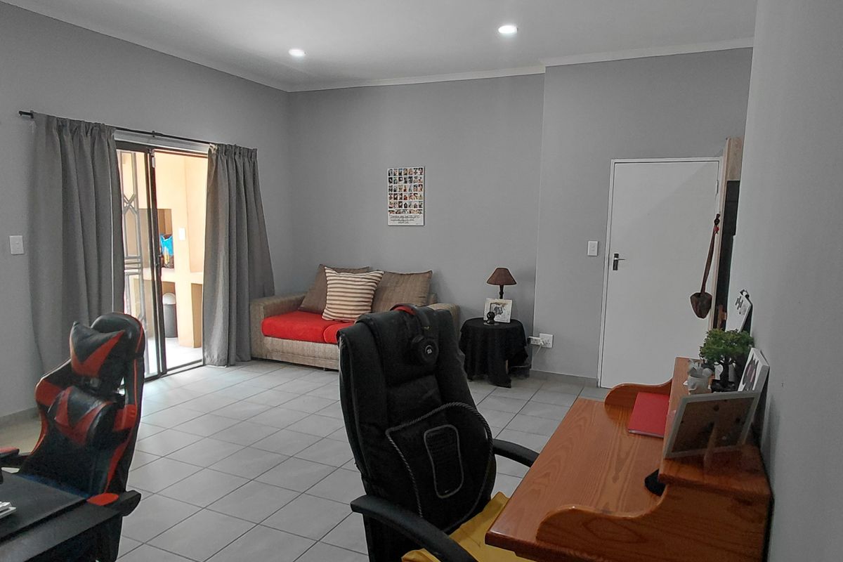 A spacious living area featuring neutral grey walls, tiled flooring, recessed lighting, and a sliding glass door providing access to an outdoor space.