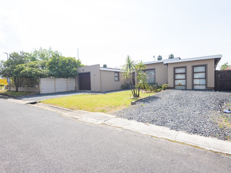 Front exterior view of a single-story house featuring a gravel driveway, attached garage, and a low-maintenance front garden with boundary walling.