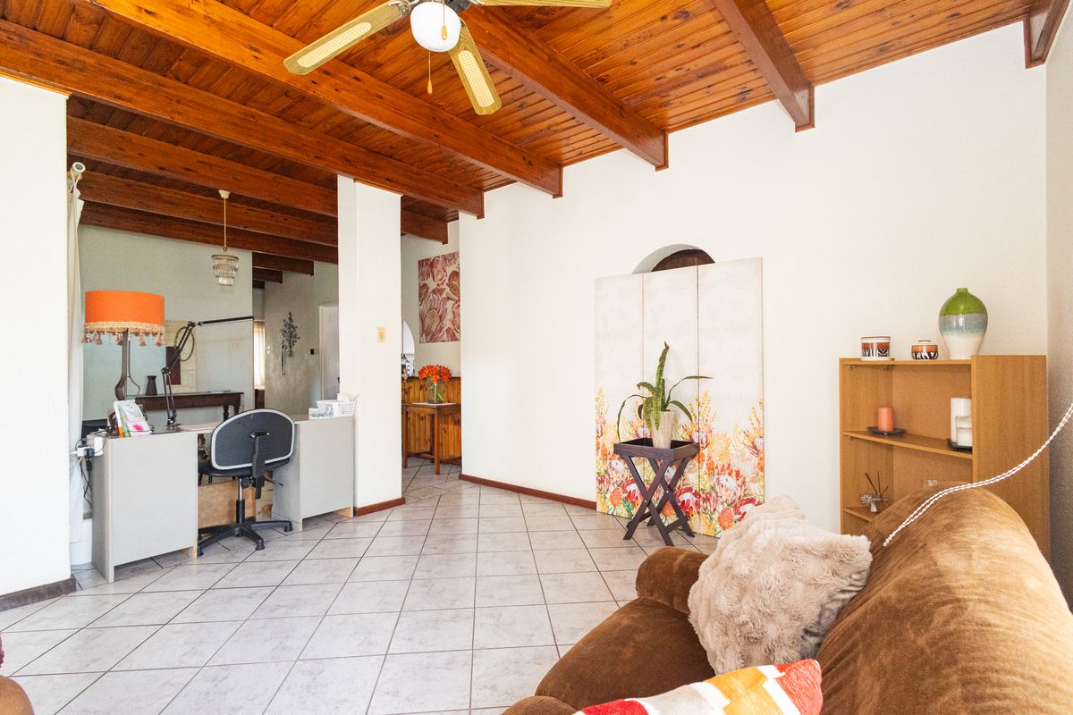 Spacious living area featuring a rustic exposed timber beam ceiling, ceramic tiled flooring, and a ceiling fan, offering a warm and inviting atmosphere.
