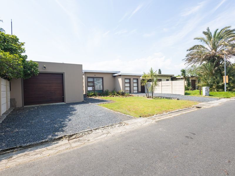 Front exterior view of a single-story house featuring a garage, gravel driveway, and a low-maintenance front garden with boundary walling.