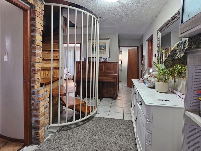 A hallway featuring a distinctive spiral staircase with a metal balustrade and an exposed brick pillar, connecting to adjacent living spaces.