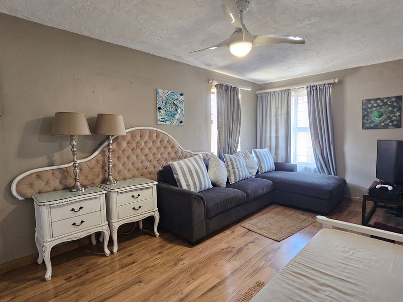 A living room featuring laminate flooring, a ceiling fan, and neutral wall tones, offering a comfortable space for relaxation.