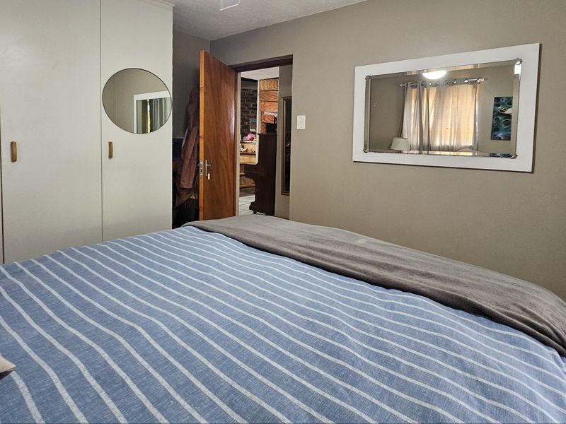 A bedroom featuring built-in cupboards and a solid wood door, providing a functional and neutral living space.
