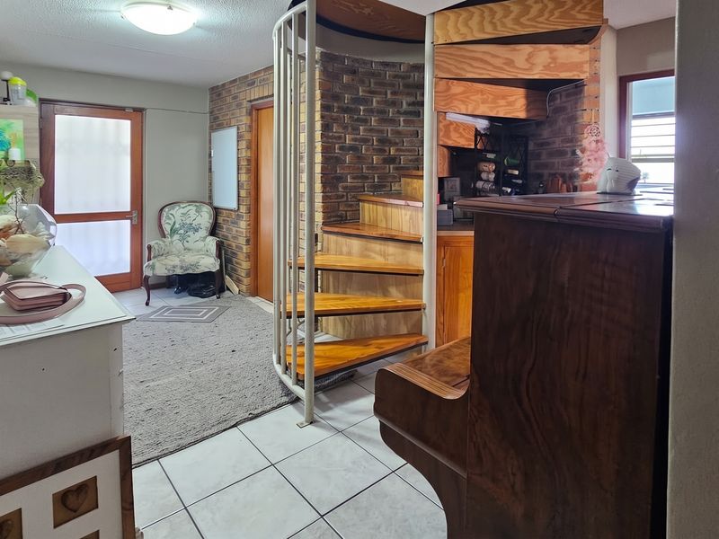 Entrance area featuring a prominent spiral staircase with timber treads and an exposed brick feature wall, finished with tiled flooring.