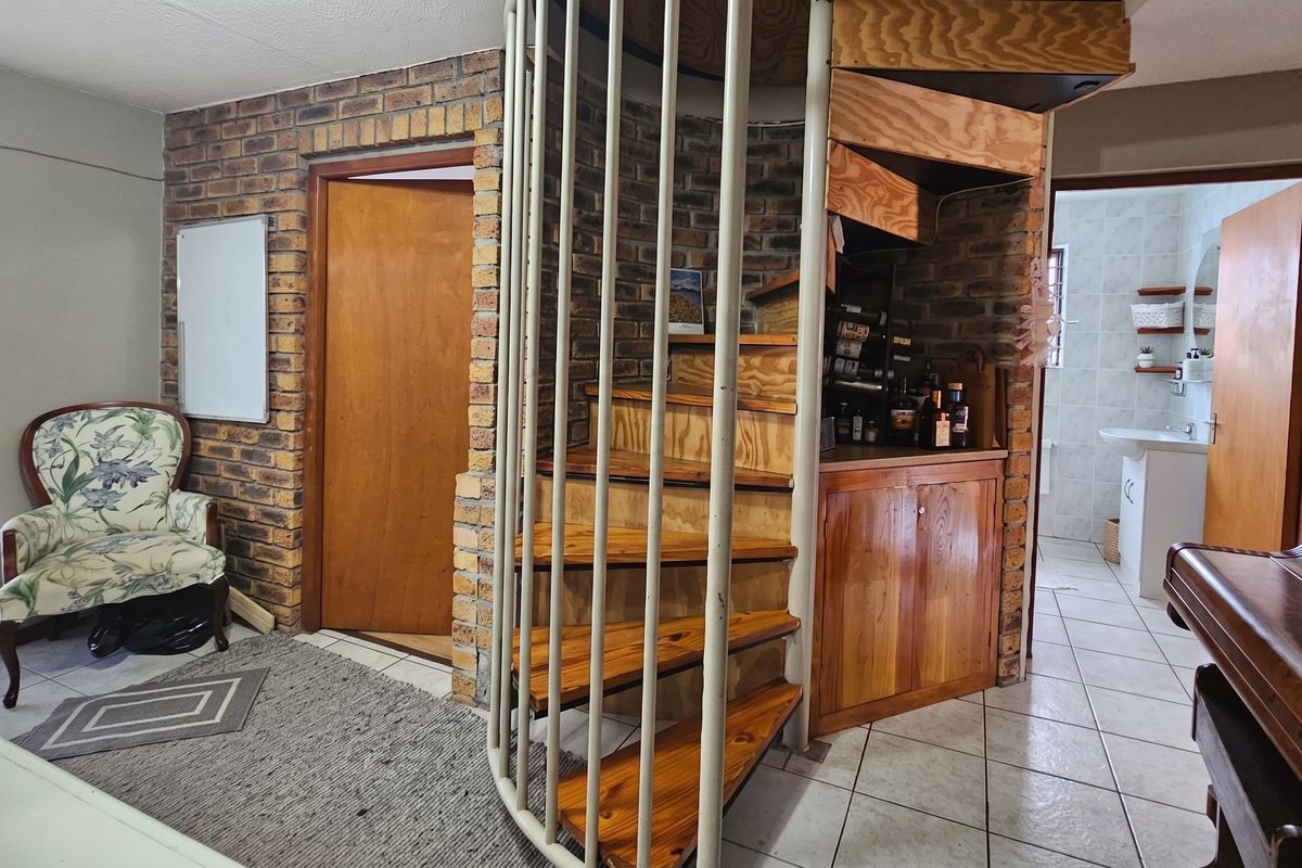 Living area featuring a prominent spiral staircase, exposed brickwork, and tiled flooring, with access to an adjacent bathroom.