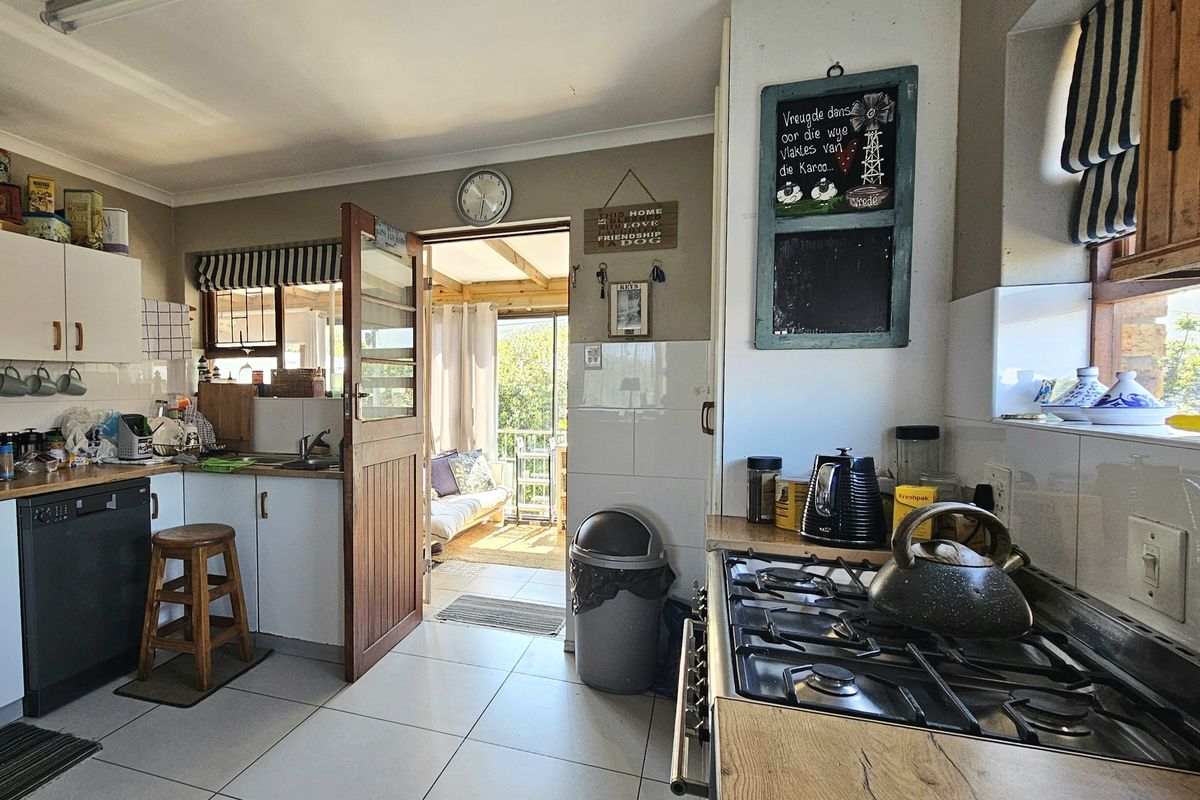 A functional kitchen featuring tiled flooring, laminate countertops, a gas hob, and built-in cabinetry, with direct access to an adjoining sunroom area.
