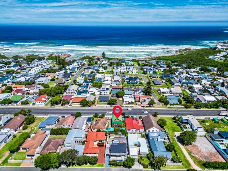 Aerial view of a coastal residential property located in a prime seaside neighborhood, showcasing proximity to the ocean and surrounding infrastructure.