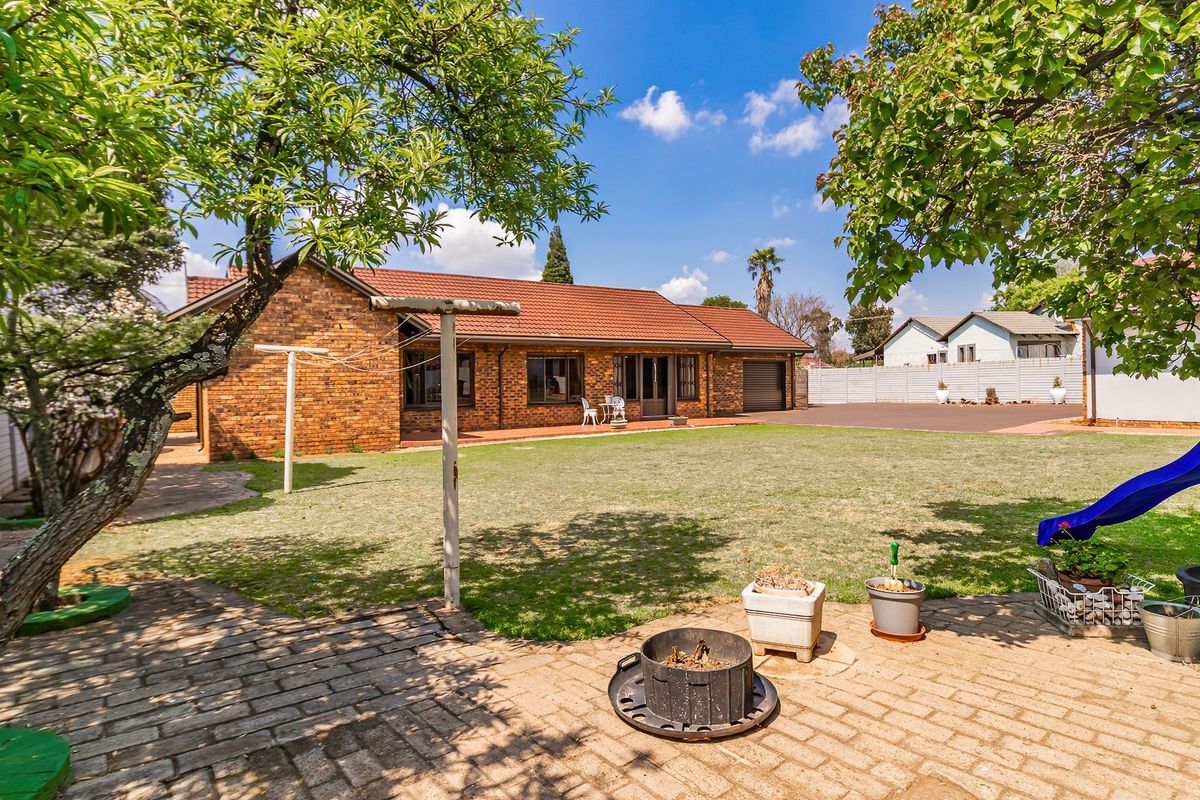 Spacious rear garden featuring a brick-faced house, paved patio area, and established lawn, providing a functional outdoor space.
