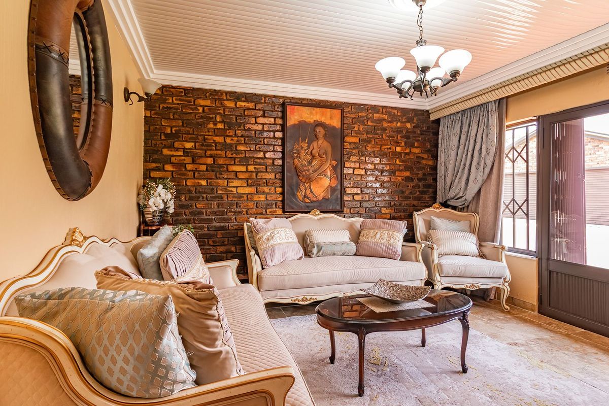 A cozy living room featuring an exposed brick accent wall, tongue and groove ceiling, and direct access to the exterior through a glass panel door.