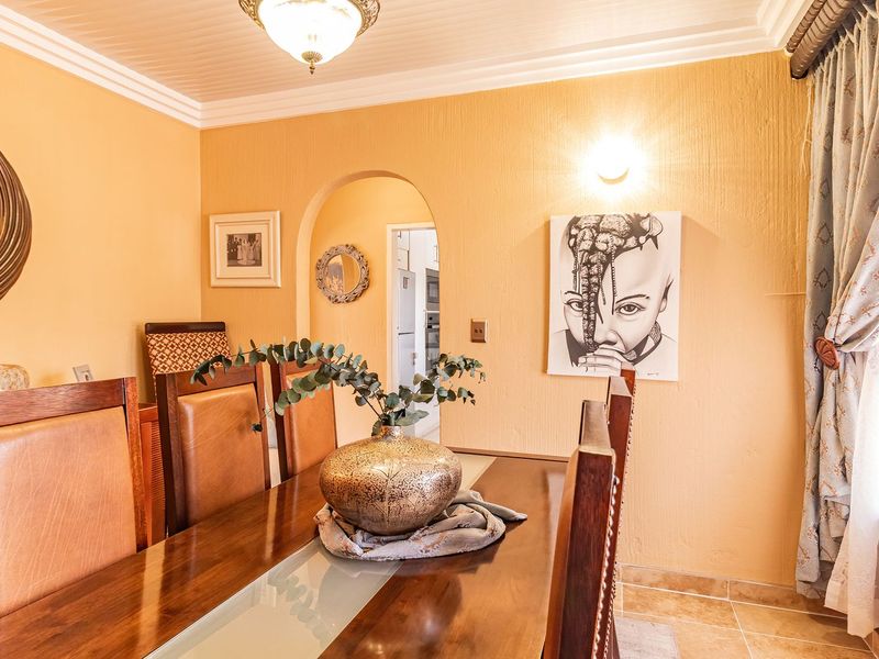 A dining room featuring tiled flooring, crown molding, and an arched doorway leading to an adjacent space.