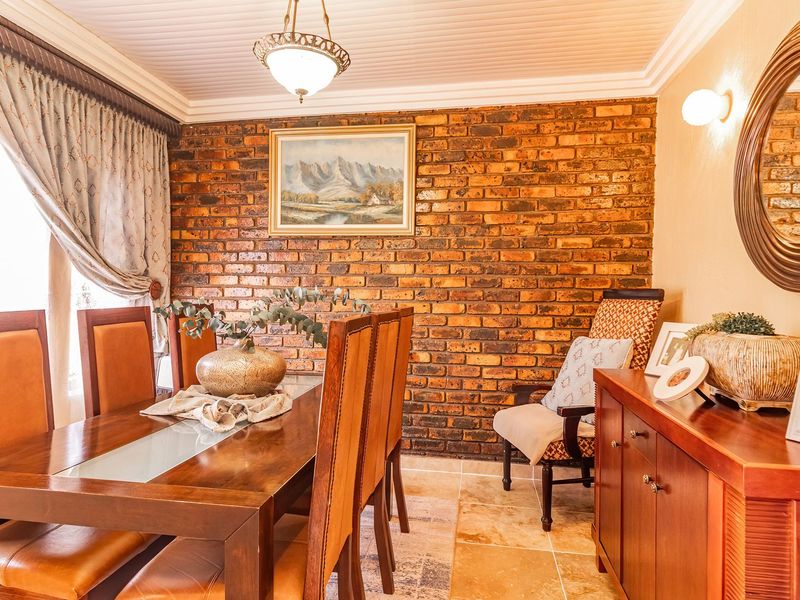 A dining room featuring an exposed brick feature wall, tiled flooring, and classic crown molding, creating a warm and traditional atmosphere.