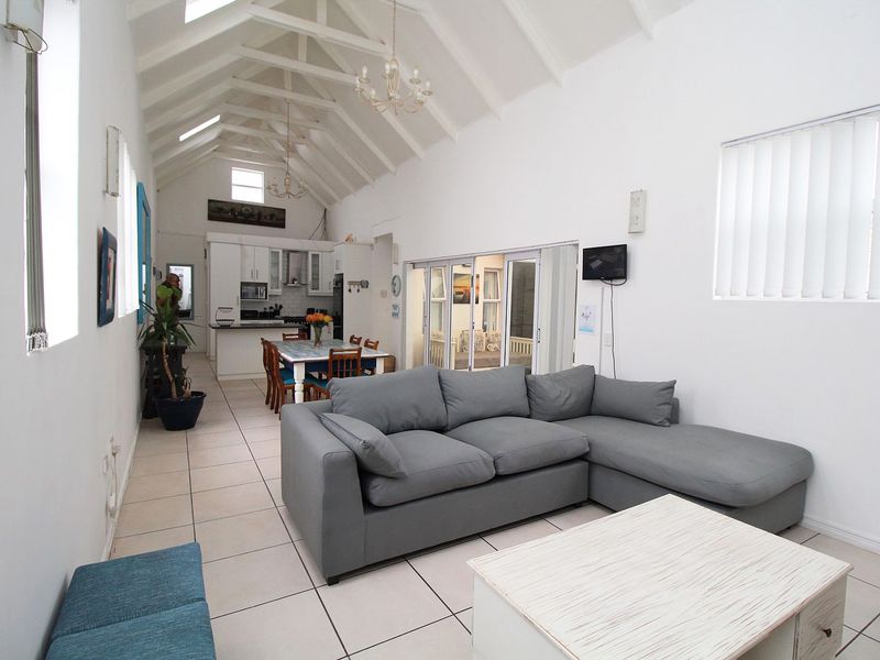 Spacious open-plan living and kitchen area featuring a high vaulted ceiling with skylights, tiled flooring, and seamless flow to the outdoor patio.