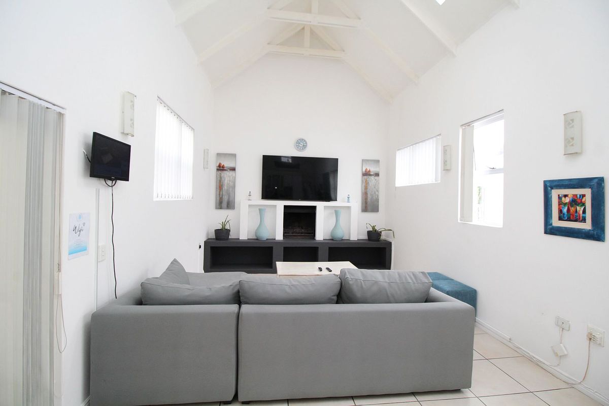 A bright living room featuring a high vaulted ceiling, tiled flooring, and a built-in media console with integrated shelving.