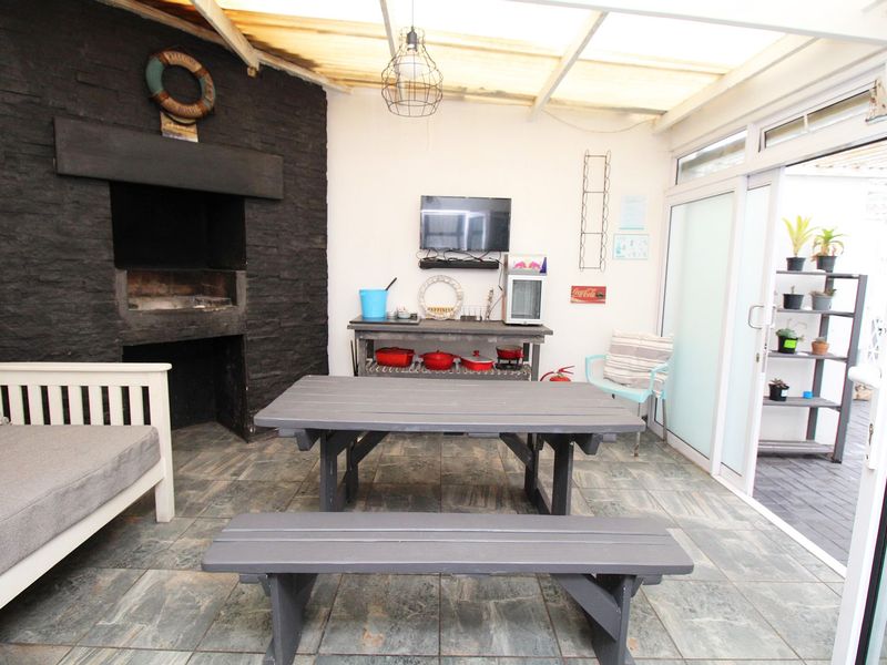 Covered patio area featuring a built-in braai with stone cladding, tiled flooring, and sliding glass doors leading to the exterior.
