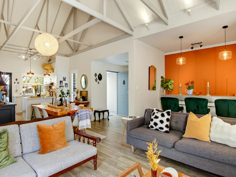 Spacious open-plan living and kitchen area featuring high vaulted ceilings with exposed trusses, modern cabinetry, and durable laminate flooring.