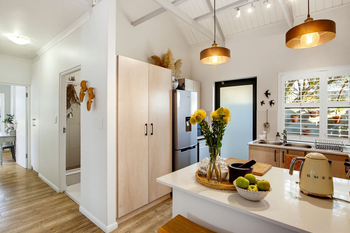 Modern kitchen featuring a central island, light wood cabinetry, vaulted ceilings with exposed rafters, and high-quality finishes throughout.