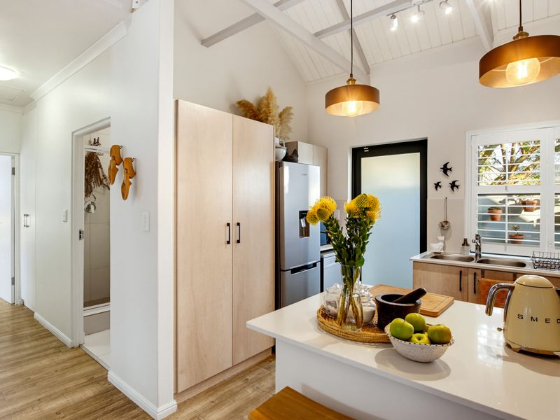 Modern kitchen featuring a central island, light wood cabinetry, vaulted ceilings with exposed rafters, and high-quality finishes throughout.