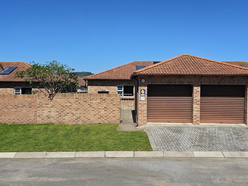 Front view of a well-maintained brick house featuring a double garage, paved driveway, and a secure boundary wall.