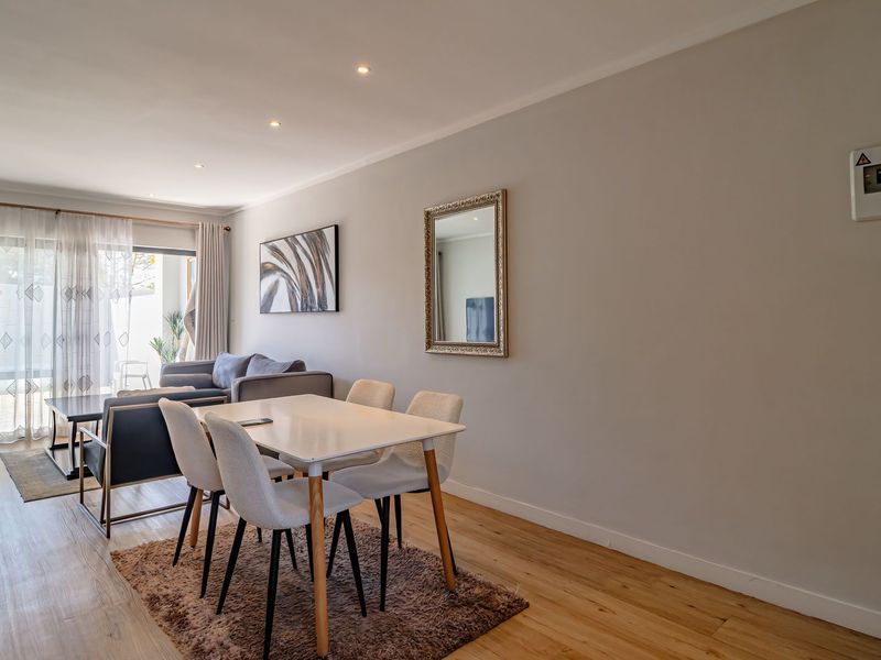 Bright open-plan living and dining area featuring modern laminate flooring, recessed lighting, and large sliding glass doors leading to an outdoor space.