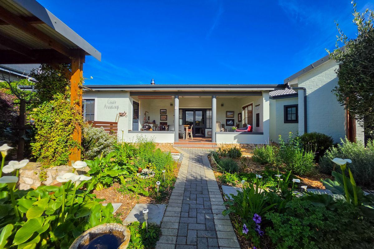 A well-maintained rear exterior view featuring a covered patio, paved walkway, and established landscaped garden.