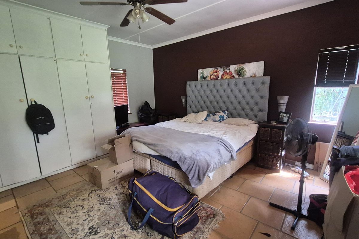 A bedroom featuring built-in cupboards, tiled flooring, and a ceiling fan, offering a functional space with potential for cosmetic updates.