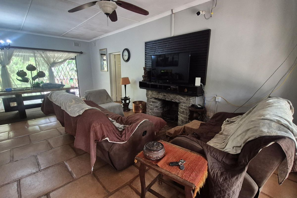 Spacious living room featuring a stone fireplace, tiled flooring, and a ceiling fan, offering a comfortable area for relaxation and family gatherings.