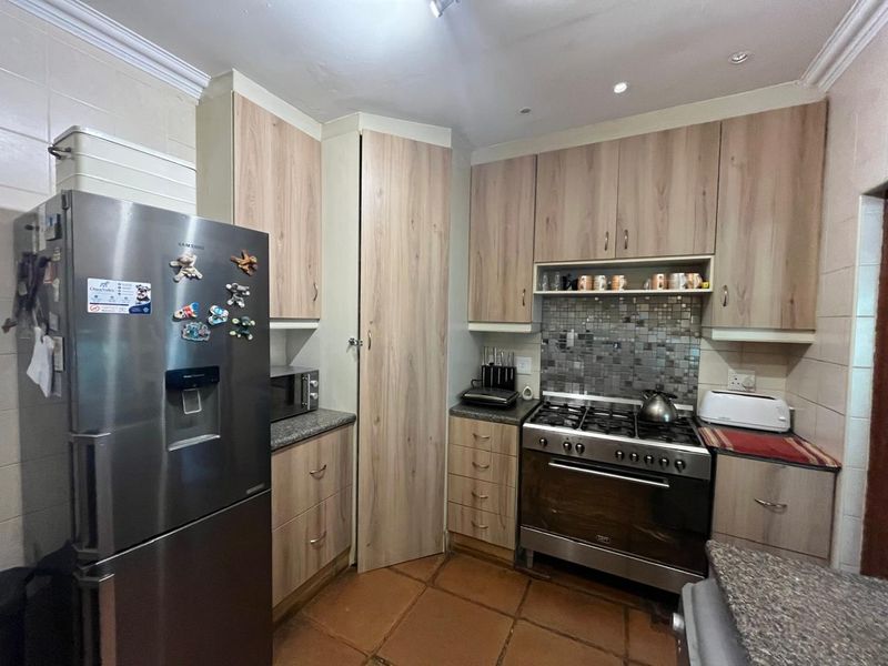 A functional kitchen featuring light wood-finish cabinetry, granite countertops, a mosaic tile backsplash, and a gas stove with oven.